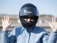 Девушка в мотоциклетном шлеме с поднятыми руками